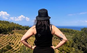 Renee with her back to the camera looking over a vineyard with blue skies