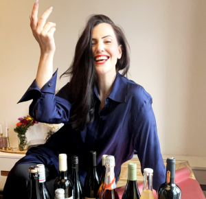 Renée in a blue blouse standing behind different wines