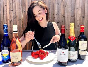 Renée at a table eating strawberries with 5 bottles of wine